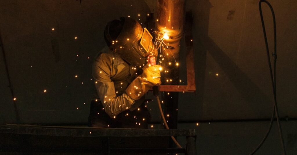 a welder at work indoors creating bright sparks while welding metal pipes